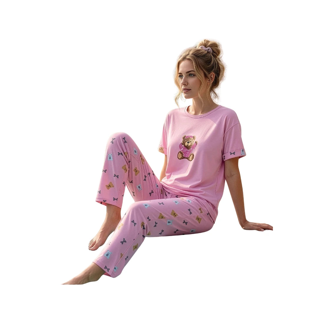 Woman wearing a pink 100% cotton short sleeve pajama set with a teddy bear print T-shirt and matching printed full-length pants.