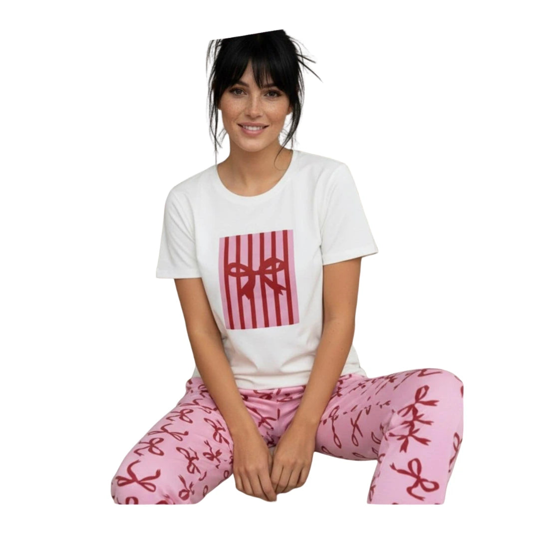 Woman wearing a white short-sleeve graphic T-shirt with matching pink ribbon-print cotton pyjama pants on a white background.