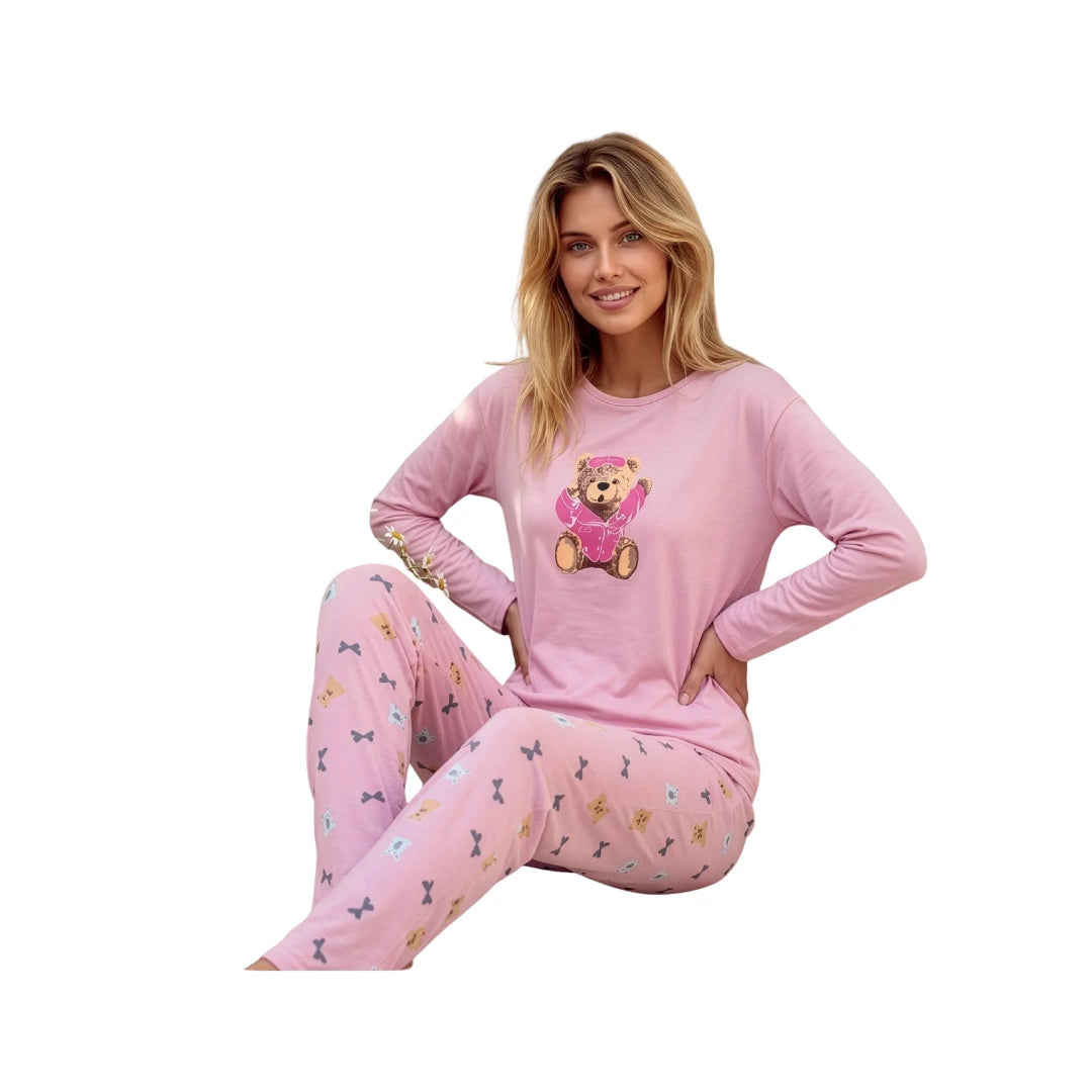 Woman wearing a pink 100% cotton long sleeve pajama set featuring a teddy bear print top and matching full-length printed pants on a white background.