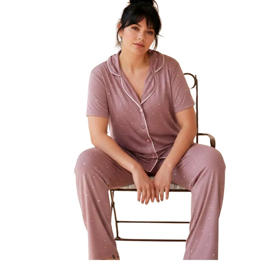 Woman wearing a soft mauve short sleeve button-up pajama set with white polka dots and full-length pants.