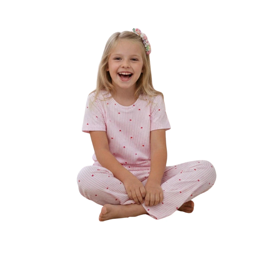 Young girl wearing a light pink striped cotton pyjama set with short sleeves and matching full-length pants featuring small polka dot details.